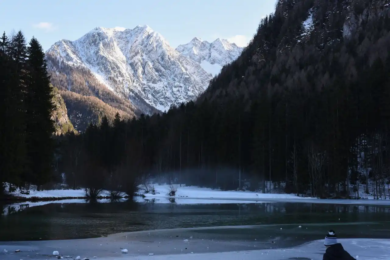 Zimska pokrajina s snežnimi gorami in mirno vodo v bližini Kranja